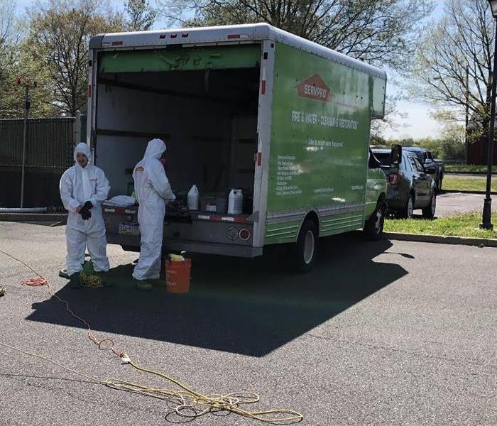 Green truck box, two technicians wearing white protective gear